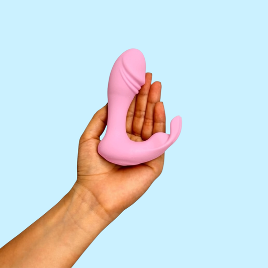 Vibrador Loto Bifurcado color rosa con brazo curvo estimulador, sostenido en la mano - Edén