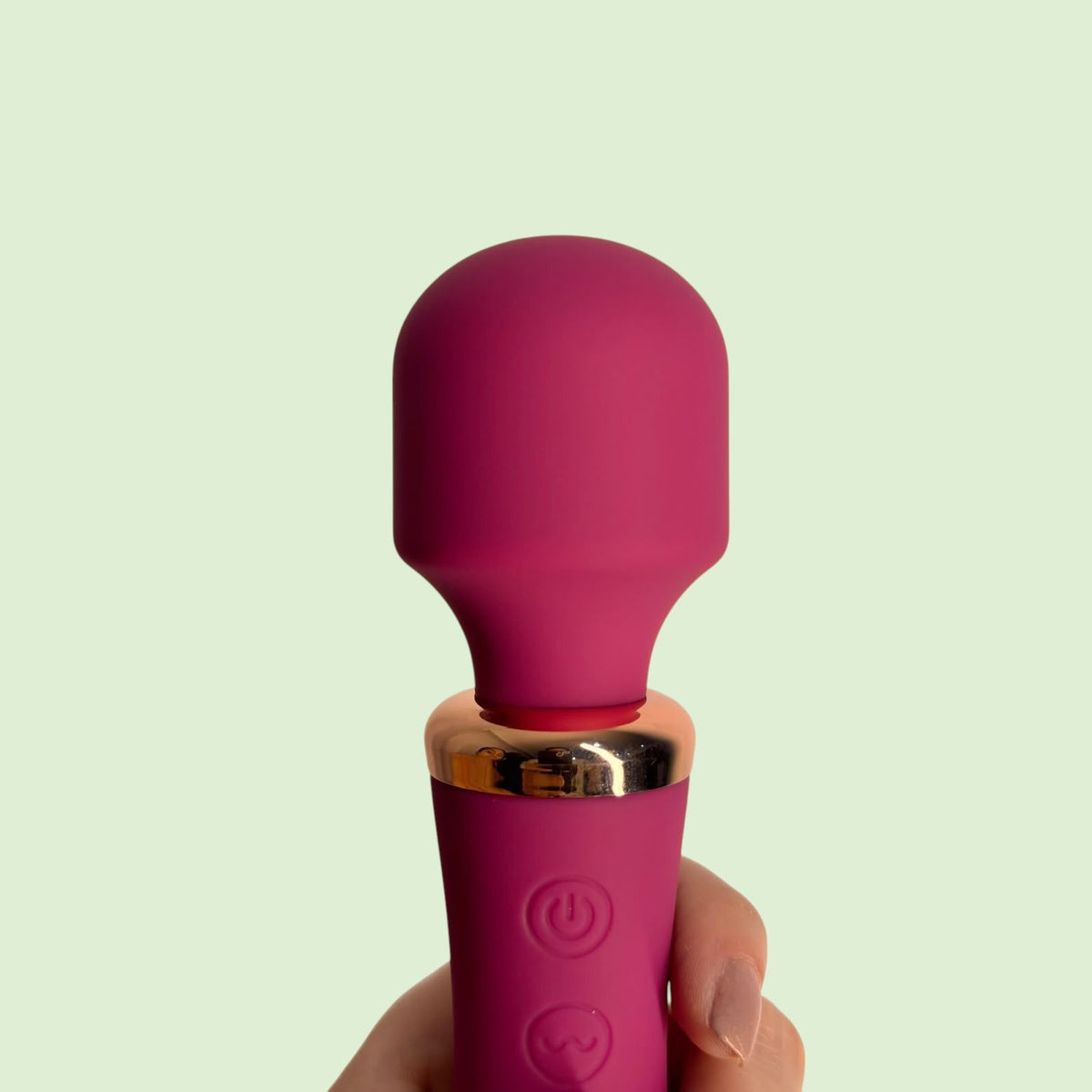 Masajeador tipo varita Cetro de Edén variante color rosa nude con base dorada, sostenido en la mano - Edén