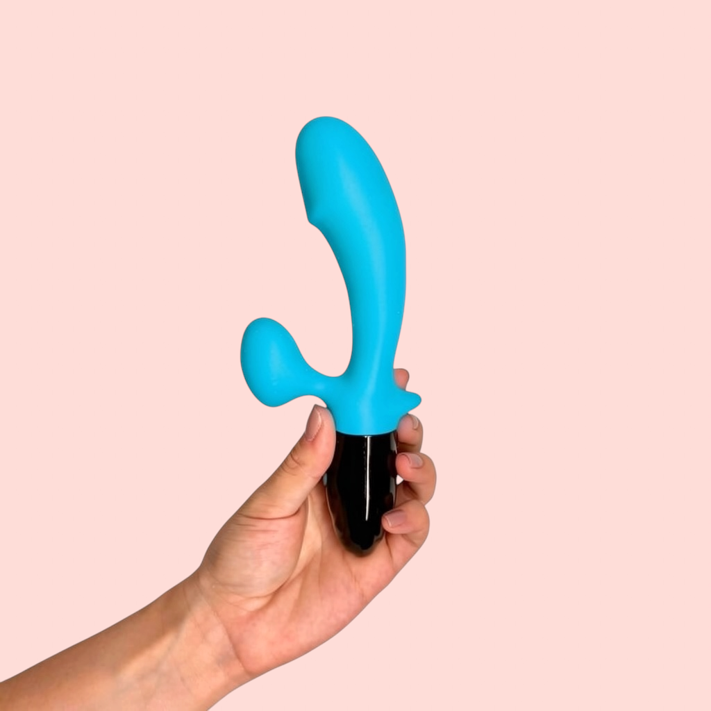 Vibrador Baya Escarlata variante color azul turquesa con base negra brillante, sostenido en la mano - Edén