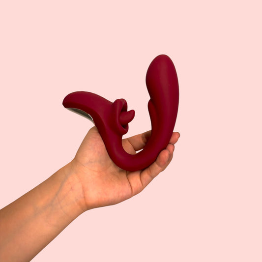 Vibrador Cáliz de Eva sostenido en la palma mostrando su curvatura completa en argolla y detalle de la lengüeta - Edén