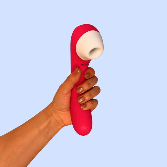 Succionador Cereza del Edén color rosa magenta con cabezal de silicona blanco, sostenido en la mano - Edén