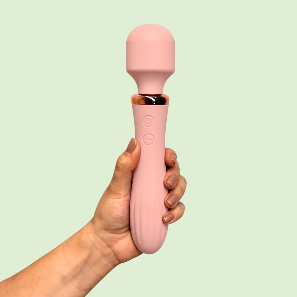 Masajeador tipo varita Cetro de Edén variante color rosa nude con base dorada, sostenido en la mano - Edén