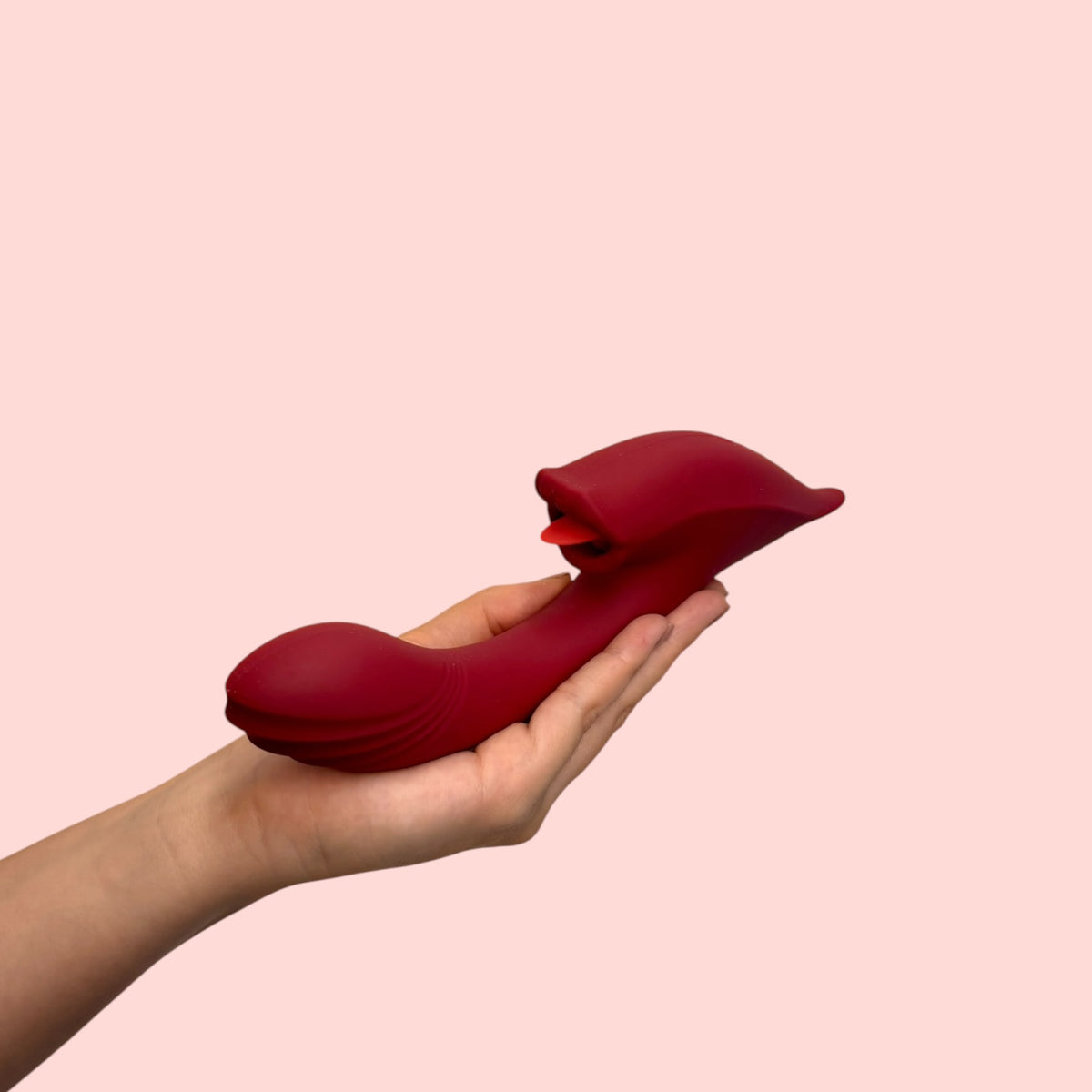 Vibrador Llama de Azahar rojo vino sostenido en la palma, vista lateral con masajeador tipo lengua - Edén
