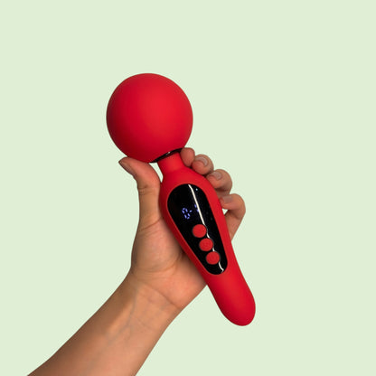 Masajeador tipo varita Orbe de Edén color rojo con pantalla digital, sostenido en la mano - Edén