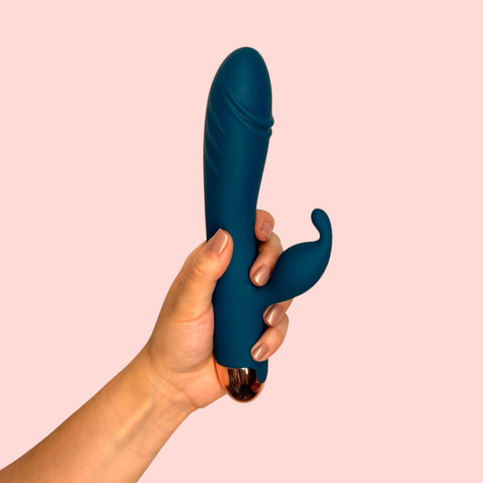 Vibrador Rocío del Alba color azul petróleo con brazo curvo estimulador, sostenido en la mano - Edén