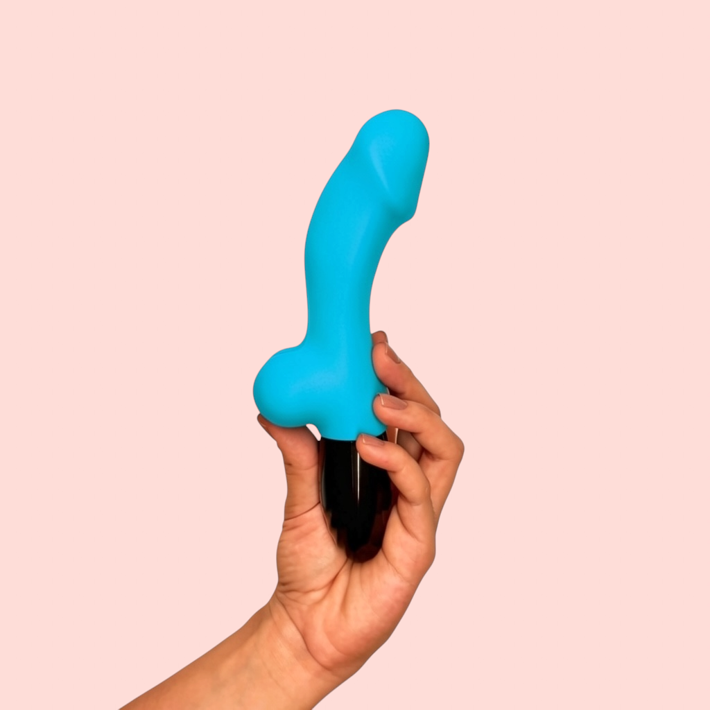 Vibrador Yema Escarlata variante color azul turquesa con base negra brillante, sostenido en la mano - Edén